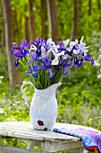 Blue and white irises in a jug on a wooden table
