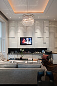 Open-plan living area with geometric wall panelling and chandelier