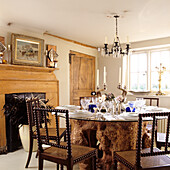 Dining room with glass table on tree trunk and chandelier