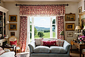 Country-style living room with patterned curtains and countryside views