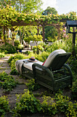 Green deckchair with white cushion and pergola over terrace in summer garden