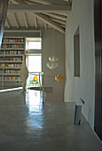 Puristisch eingerichteter Wohnraum mit Bücherregal, modernen Lampen und Betonboden