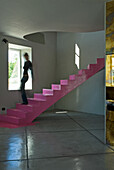 Spiral staircase with pink steps in modern room with stone tiled floor