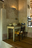 Rustic dining table with antique chair on plastered wall in country house style