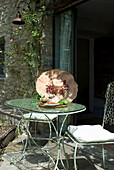 Metal patio table with decoration and stone façade in the background