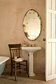 Wooden chair and antique oval mirror in the vintage bathroom