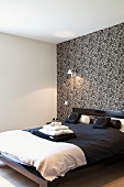 Black and white bedroom - double bed with black bed linen against wall with black and white patterned wallpaper