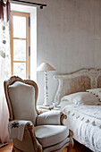 Romantisches Schlafzimmer mit Vintage-Bett und Polstersessel