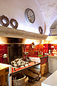 Rustikal Landhausküche mit offenem Kamin und roten Fliesen an der Wand