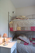 Etagenbett mit Patchwork-Bettwäsche und Nachttischlampe im Kinderzimmer