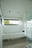 Designer bathroom with built-in bathtub below ribbon window
