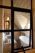 View through window into simple attic bathroom with wooden ceiling