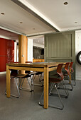 Modern kitchen with wooden dining table and metal chairs in front of olive green sliding door