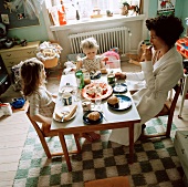 Mutter und kleine Töchter beim gemeinsamen Essen in lebendigem Kinderzimmer