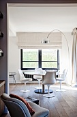 White shell chairs at round table and fifties-style arc lamp