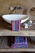Designer washbasin and wall-mounted taps combined with rustic washstand made from reclaimed wood