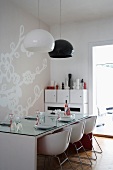 Modern dining area in black and white with glass table top, shell chairs and subtle mural