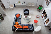 Wohnzimmer mit L-förmigem Ledersofa, orangefarbenen Kissen und Kamin