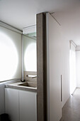 Schmales, modernes Badezimmer mit Betonwaschtisch und weißen Rollos