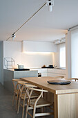 Minimalistische Küche mit hellem Holz-Esstisch und modernen Deckenspots
