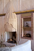 Open fireplace with Oriental elements, ornate copper vessels in niche and collection of candlesticks