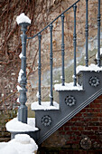 Verschneite Außentreppe mit schmiedeeisernem Geländer