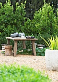 Rustic table with four stools on area of gravel in garden