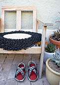 Wooden chair with black and white seat cushion, succulents and sandals