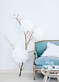 Hand-made fantasy tree objet with enormous tissue paper chrysanthemums next to powder blue, shabby chic sofa and old wicker table