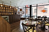 Innenraum vom Bosie Tea Café mit großer Glasfront und goldenen Teedosen auf langem Wandregal über der Theke (Manhattan, New York)