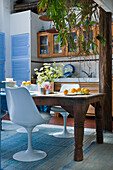 Kitchen with rustic wooden table, white chairs and white cabinets with light blue louvre doors