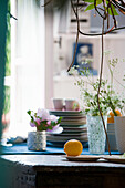 Lemon still life on a rustic wooden table with crockery, flowers and vases