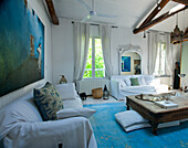 Living room with rustic wooden beams, white furniture and blue carpet