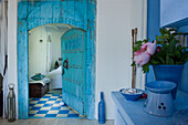 Blick in Schlafzimmer, blaue Holztür im orientalischen Stil, blau-weiß karierter Boden