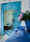 Turquoise-coloured wooden door, blue and white tiled floor and antique chest