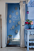 Light blue wall with Hamsa wall decoration, patterned carpet, peonies and white curtain