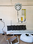Loft-apartment-style living room with Bauhaus pendant lamp above armchair and ottoman in front of sofa