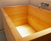 Contemporary wooden bathtub with wall-mounted tap fitting