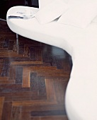 White, curved designer sofa on dark parquet flooring