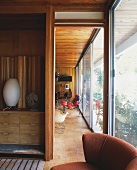 View of wood-panelled living room and large windows through open door