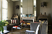 Cosy living room with fireplace, grey velvet sofas and antique sculptures