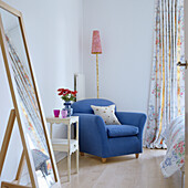 Bright reading corner with blue armchair and floral curtain