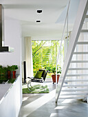 Bright room with staircase, green accent carpet and plants