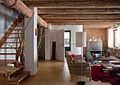 Offener Wohnraum mit rustikaler Holzbalkendecke und Treppenaufgang