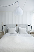 Hell gestaltetes Schlafzimmer mit Doppelbett und weißer Bettwäsche