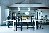Spacious country-style dining room with white wooden table and black chairs