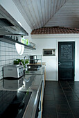 Modern kitchen with black floor tiles and black door that acts as a blackboard