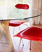 Wooden, red-stained chairs at glass table with metal foot