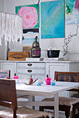 Weißer Esstisch mit Stühlen und bunter Wandkunst in einem Wohnraum