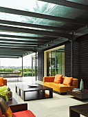 Modern colonial style seating in dark, African wood on glass-roofed terrace with vista